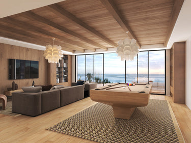 Modern living room with a luxury oak pool table, large windows, and ocean view.
